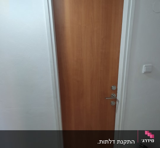 דלת עץ חומה עם ידית מתכת כסופה